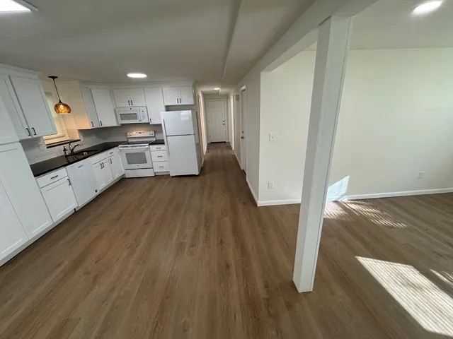 a large kitchen with a wooden floor and electronic appliances