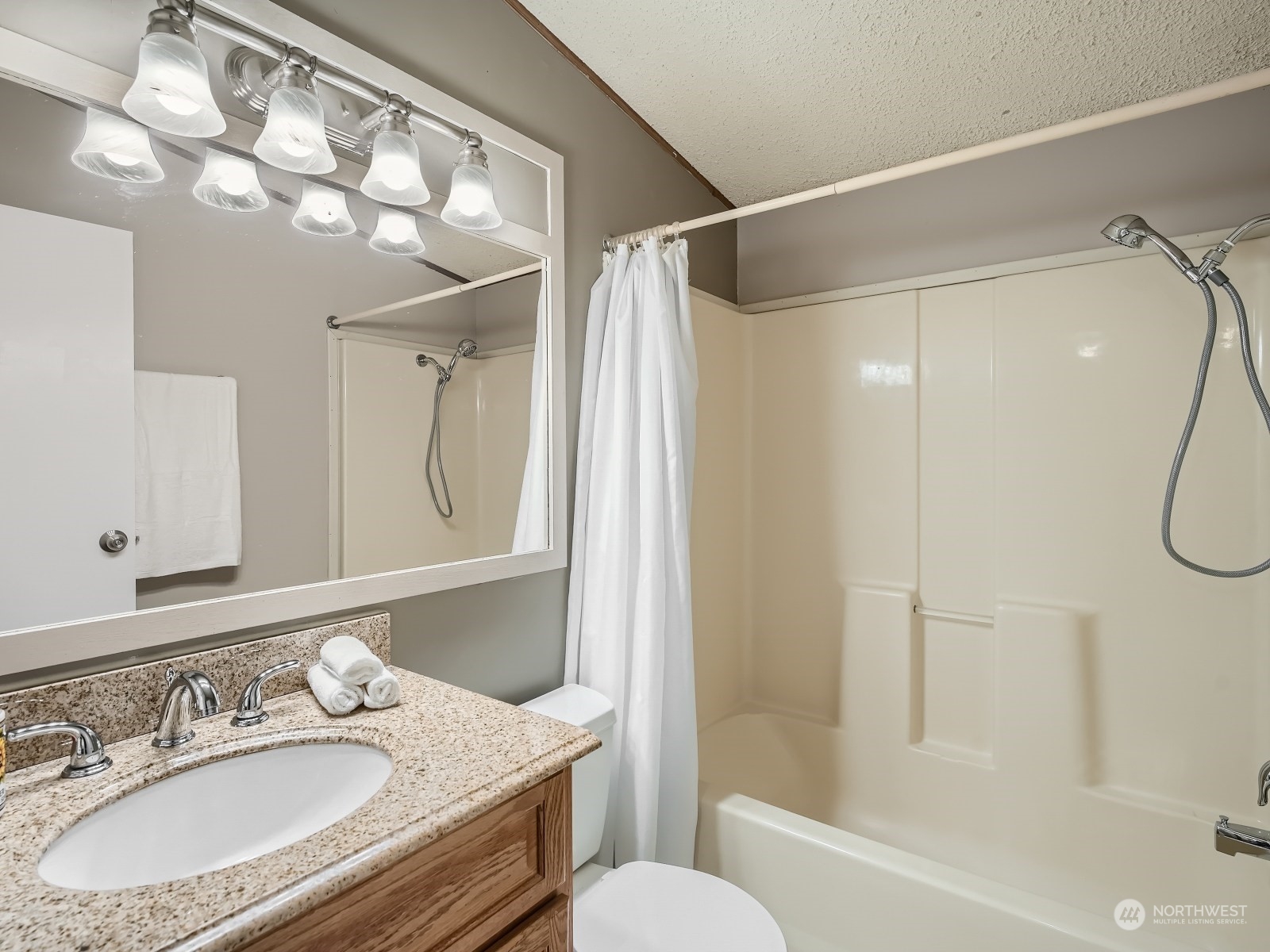 2505 South 371st Street, Unit 37 Federal Way, WA 98003 - Photo 16 of 27 a bathroom with a granite countertop sink a mirror a bathtub and shower