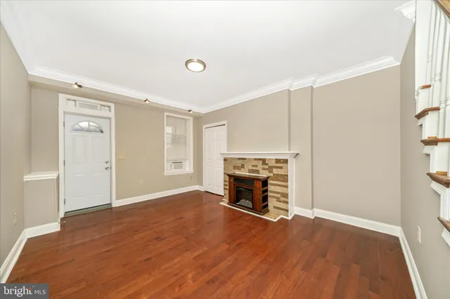 an empty room with wooden floor a fireplace and windows