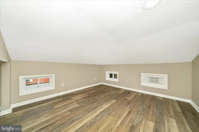 a view of a big room with wooden floor and windows