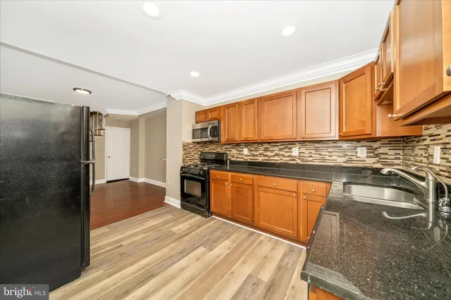a kitchen with granite countertop a refrigerator and a stove top oven