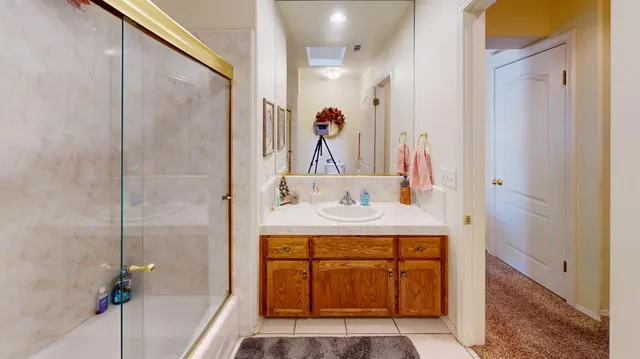 a bathroom with a granite countertop sink a mirror and shower