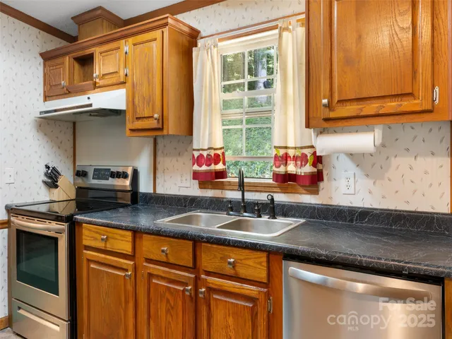 a kitchen with stainless steel appliances granite countertop a sink a stove and cabinets