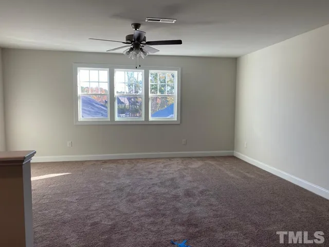 an empty room with windows and chandelier fan