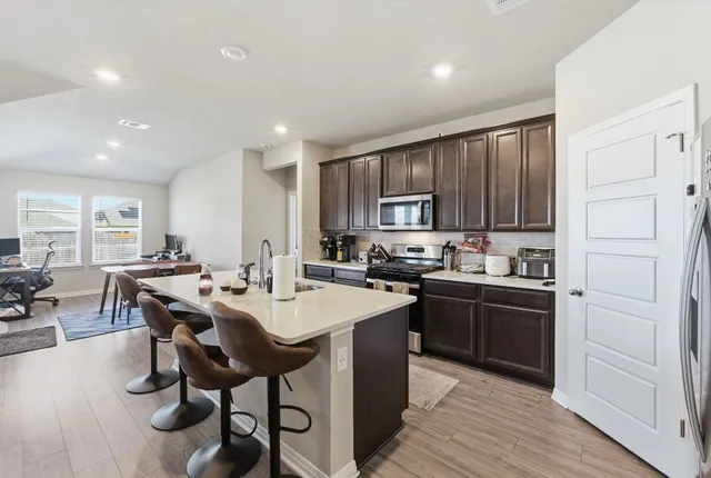 a kitchen with stainless steel appliances granite countertop a table chairs sink refrigerator and cabinets