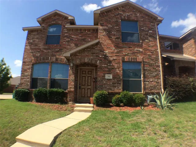 a brick building sitting in front of a brick house with a large windows