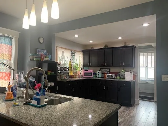 a kitchen with kitchen island granite countertop a sink appliances and cabinets