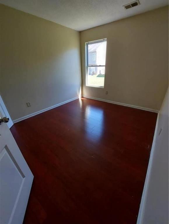 1749 Broad River Road Atlanta, GA 30349 - Photo 7 of 10 an empty room with wooden floor and windows with curtains