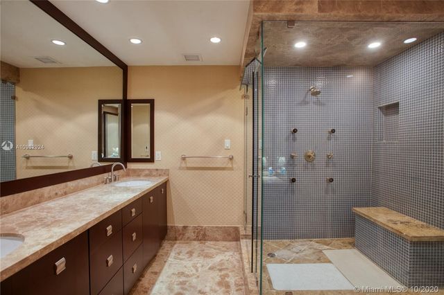 a bathroom with a granite countertop sink a toilet a mirror and shower