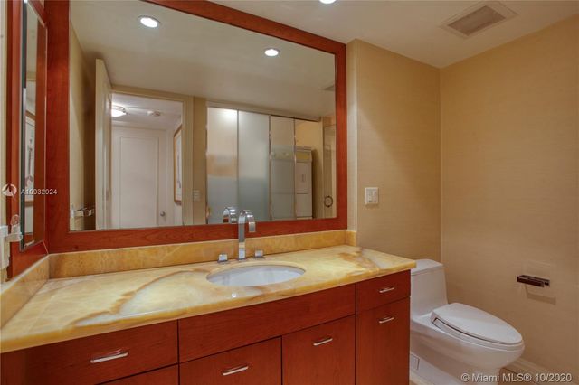a bathroom with a granite countertop sink a toilet and a mirror