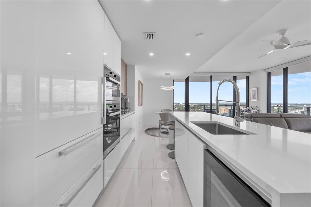 730 North Ocean Boulevard, Unit 1501 Pompano Beach, FL 33062 - Photo 13 of 56 a large white kitchen with a large window and stainless steel appliances