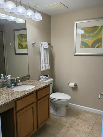a bathroom with a granite countertop toilet sink and mirror