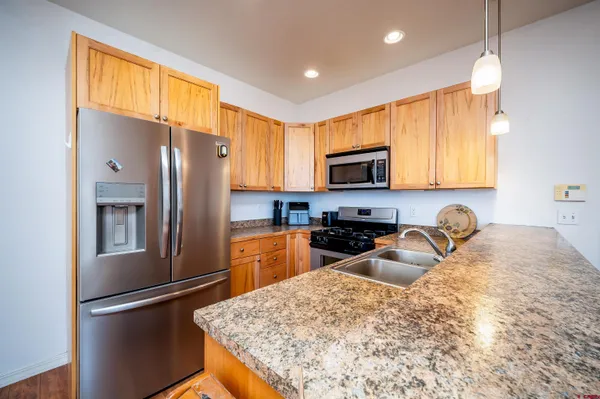 a kitchen with granite countertop a refrigerator stove top oven and sink