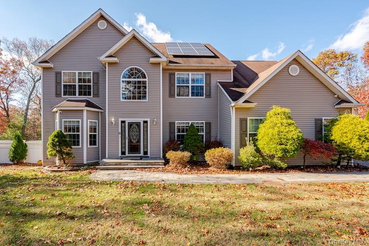 View of front facade featuring roof mounted solar panels and a front yard