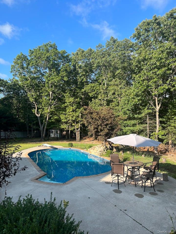 1 Brittany Court Ridge, NY 11961 - Photo 34 of 40 a view of a swimming pool with lawn chairs under an umbrella