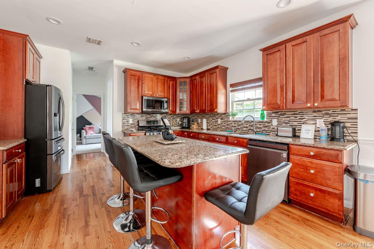 1 Brittany Court Ridge, NY 11961 - Photo 6 of 40 a kitchen with stainless steel appliances granite countertop a refrigerator a stove top oven a sink dishwasher and wooden cabinets with wooden floor