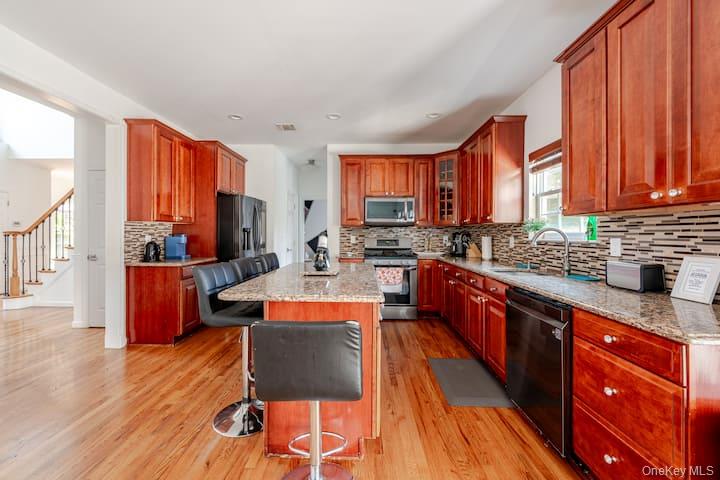 1 Brittany Court Ridge, NY 11961 - Photo 7 of 40 a large kitchen with stainless steel appliances wooden floor a large window and a sink