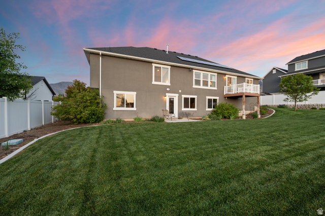 1145 North Christley Lane, Unit 48 Elk Ridge, UT 84651 - Photo 32 of 38 Expansive backyard featuring a large green lawn, concrete patio, and upper-level deck with white railing