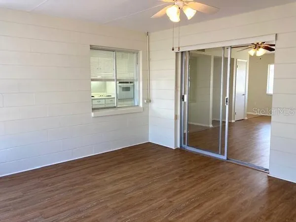 an empty room with wooden floor fan and windows