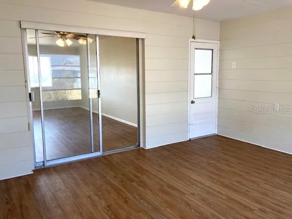 an empty room with wooden floor mirror and windows