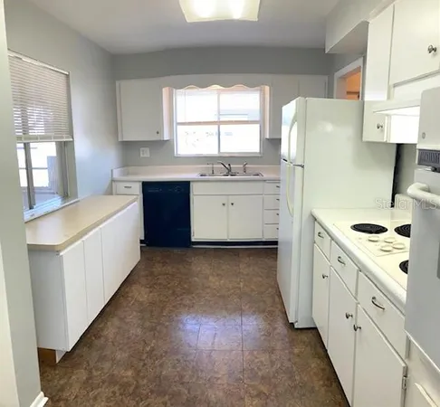 a kitchen with a sink a stove a refrigerator and white cabinets