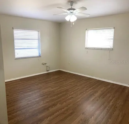 a view of empty room with wooden floor and fan