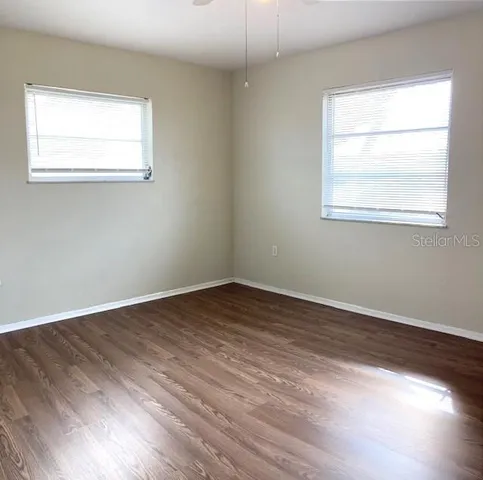 an empty room with wooden floor and windows