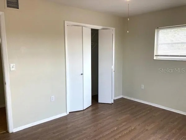 an empty room with wooden floor and window