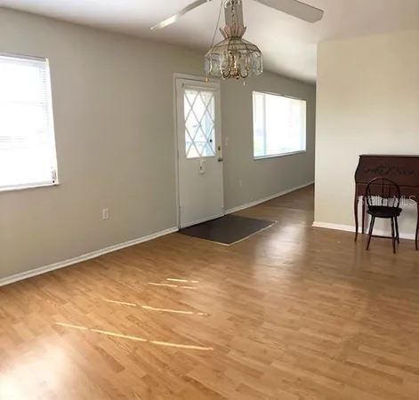 a view of empty room with wooden floor and fan