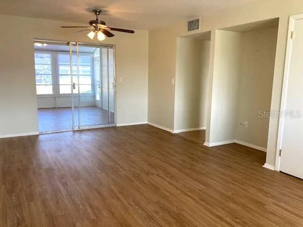 a view of empty room with wooden floor and fan
