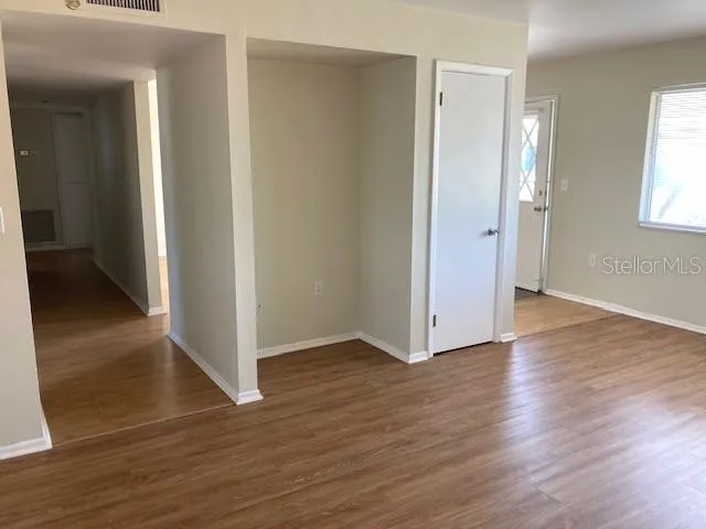an empty room with wooden floor and windows