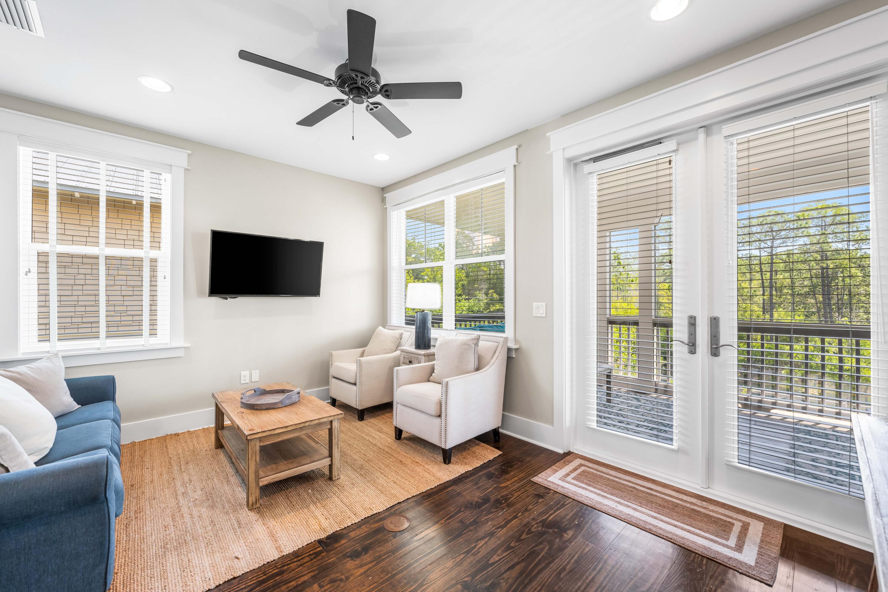 979 Sandgrass Boulevard Santa Rosa Beach, FL 32459 - Photo 21 of 72 a living room with furniture floor to ceiling window hardwood floor and a flat screen tv