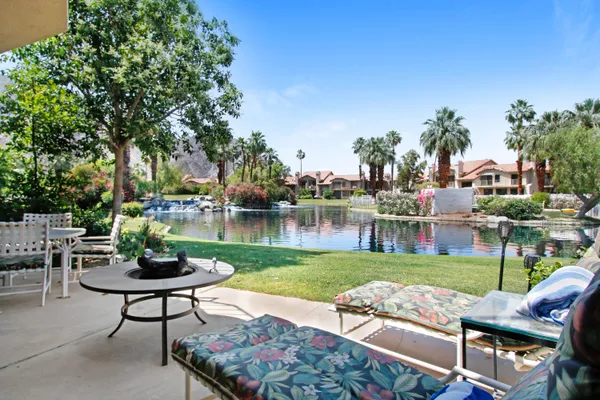 a view of a patio with table and chairs potted plants and palm tree