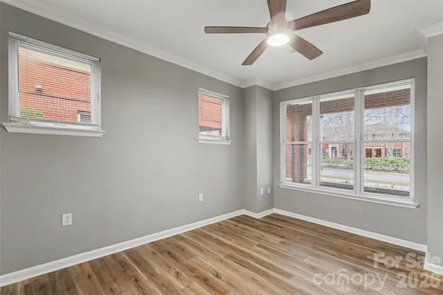 a view of an empty room with a window and wooden floor