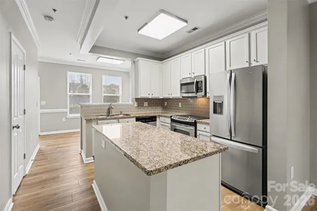a kitchen with kitchen island granite countertop stainless steel appliances a sink stove refrigerator and a window