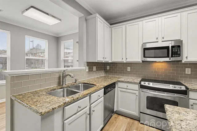 a kitchen with stainless steel appliances granite countertop a sink stove and microwave