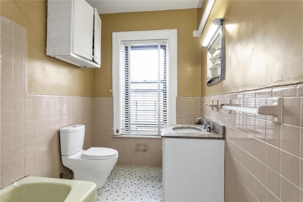 264 Decatur Street Brooklyn, NY 11233 - Photo 25 of 27 a bathroom with a granite countertop toilet a sink and a window