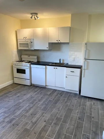 a kitchen with granite countertop a stove a sink and a refrigerator