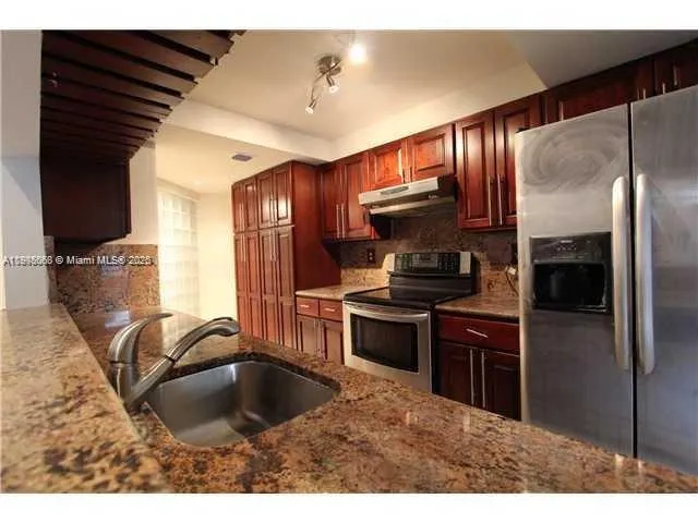a kitchen with kitchen island granite countertop a sink stainless steel appliances and cabinets