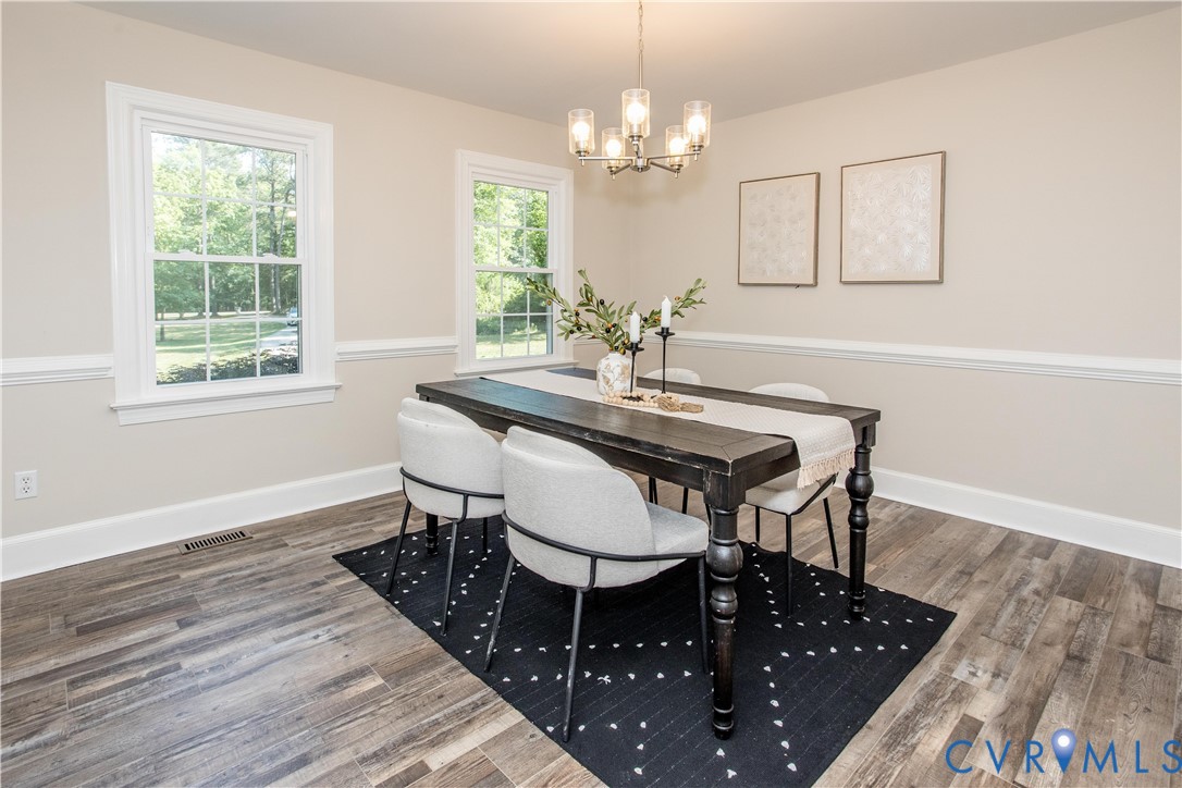 13110 Hensley Road Midlothian, VA 23112 - Photo 8 of 24 a dining room with wooden floor a chandelier a wooden table and chairs
