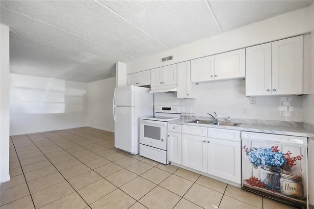 a kitchen with granite countertop white cabinets and white appliances