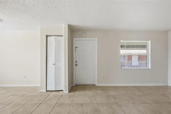 a view of an empty room with window and chandelier fan