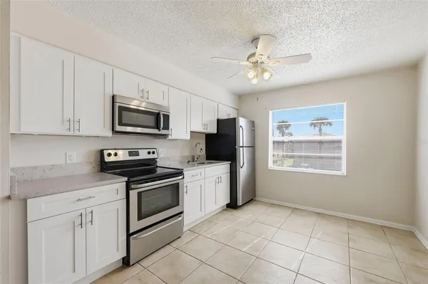 a kitchen with stainless steel appliances granite countertop a refrigerator a stove a microwave oven with white cabinets