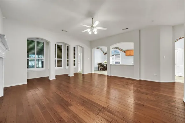 a view of empty room with wooden floor and fan