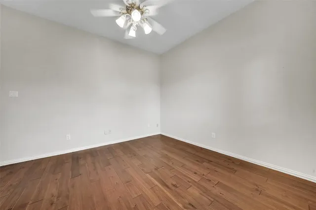 a view of an empty room with wooden floor and a chandelier