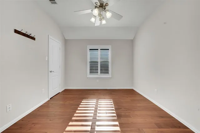 a view of a room with wooden floor a ceiling fan and windows