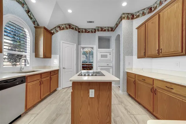a kitchen with kitchen island granite countertop a sink stove and cabinets
