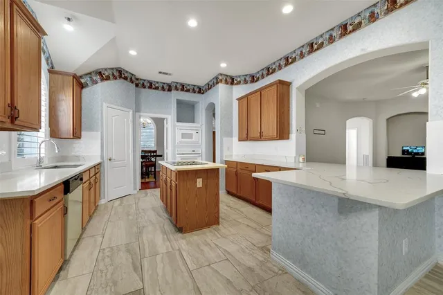 a large kitchen with stainless steel appliances kitchen island granite countertop a sink and cabinets