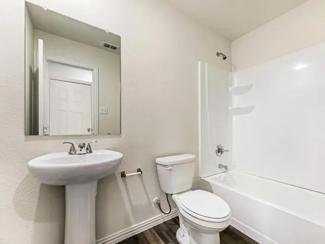 a view of an empty room with closet and wooden floor