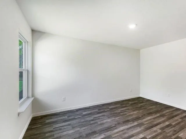 an empty room with wooden floor and a window